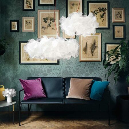 2 weiße Pendelleuchten in unterschiedlichen Größen, die wie Wolken aussehen. Im Hintergrund ein schwarzer Sessel vor einer Wand mit salbeigrüner Tapete und Retro-Blumenbildern, daneben ein Beistelltisch mit einer Tischleuchte im selben Stil