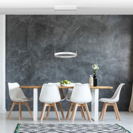 Moderne Pendelleuchte vor einer Beton-Effektwand, die über einem schlichten Esstisch mit Naturholzplatte hängt. Darum herum 6 weiße Schalenstühle mit Holzfüßen, im Vordergrund ein Teppich im Ethno-Design